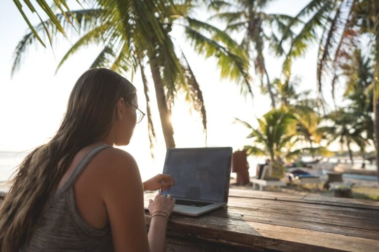 Digital nomad working on laptop under palm trees