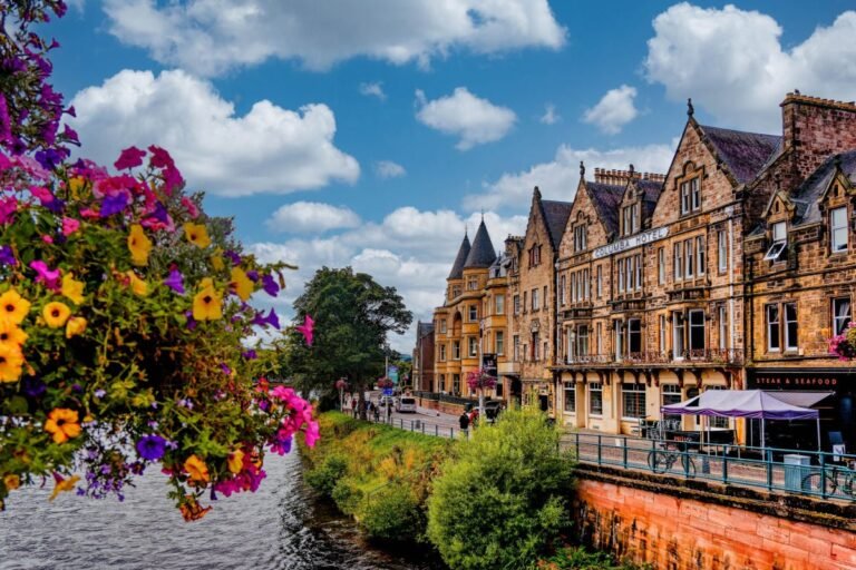 Victorian-era buildings line a busy street in Inverness, Scotland during summer