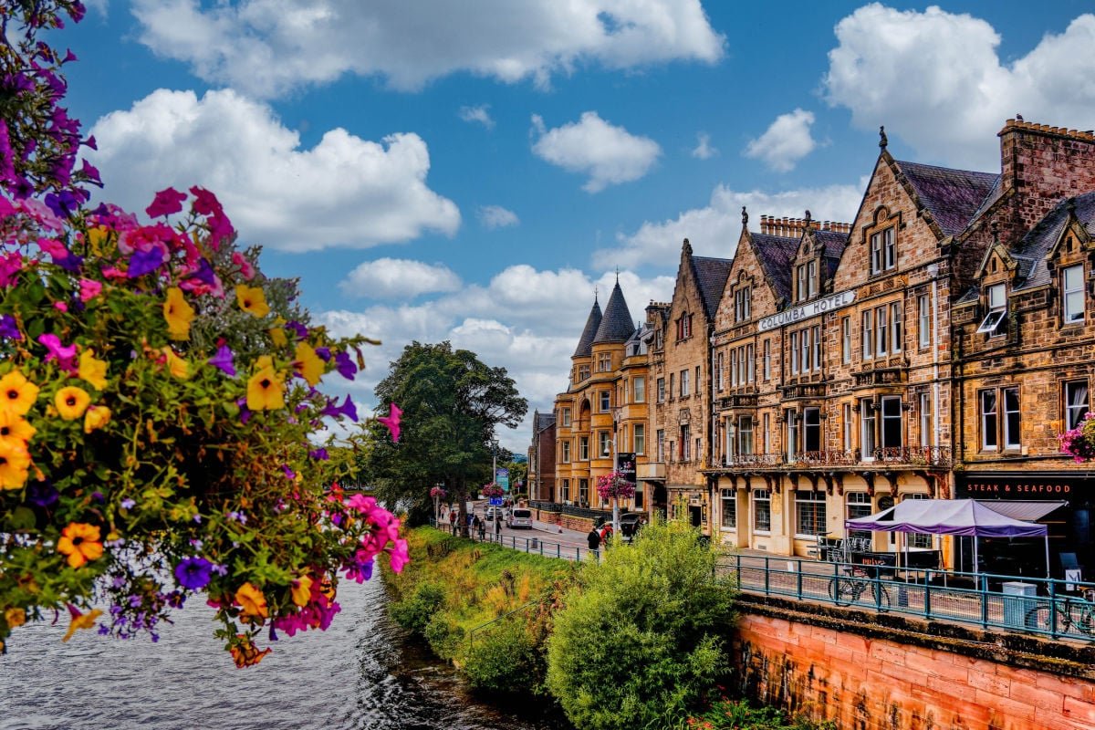 Victorian-era buildings line a busy street in Inverness, Scotland during summer